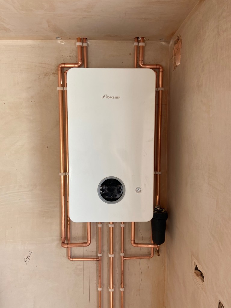 New Worcester Bosch boiler installation with neatly routed copper pipework completed by Coastal Heating Solutions in West Sussex.